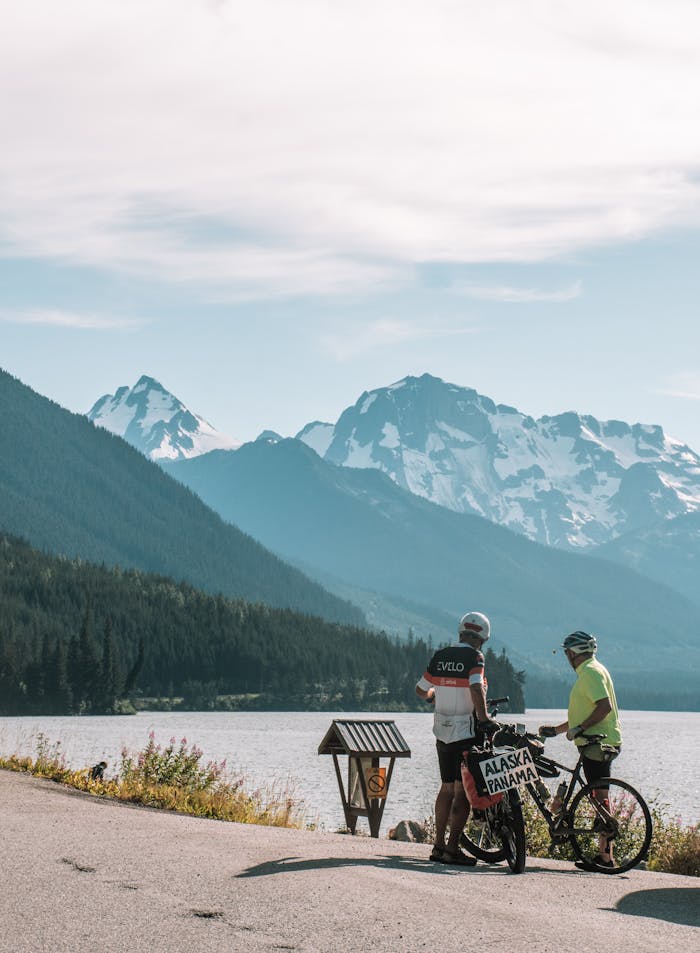services-03 Two cyclists admire a stunning mountain view by a lake in Alaska.
